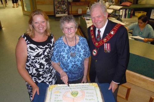 Pine Meadow Administrator Bonnie George and resident Irene Copeland, along with NF Mayor Bud Clayton, cut the anniversary cake at Pine Meadow's 20th anniversary celebration